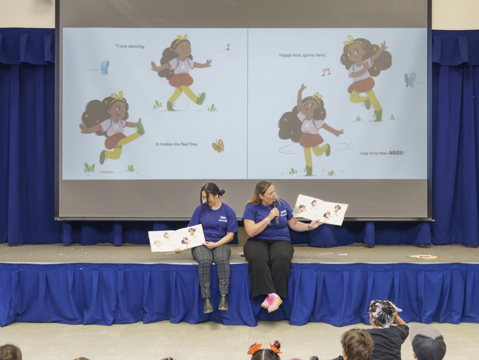 Volunteers in front of a stage with a projected book on the background